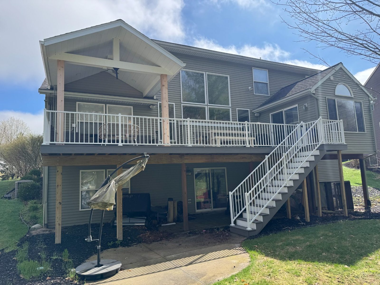 After photo of upgraded backyard deck project in Grand Rapids with white railing and covered roof structure